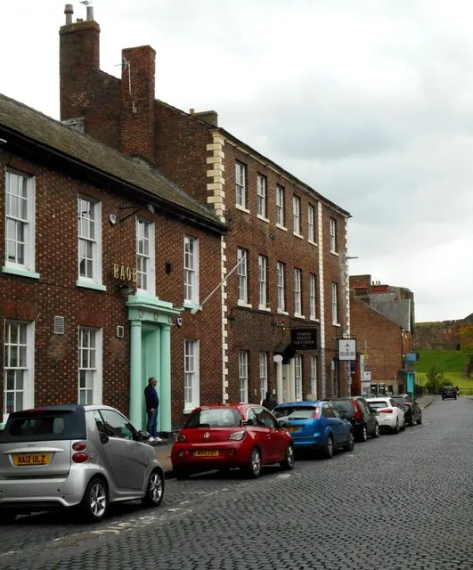 Red brick Georgian building with tall white sash windows and the letters RAOB in brass above a pale green pilastered doorway, next to a larger three-storey brick building with a Fisher Street Galleries sign. Cars are parked along the cobbled street in front.