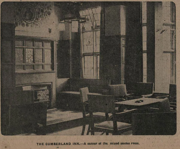 Old newspaper photograph of a corner of a smoke room with leaded stained-glass windows, a tiled fireplace, upholstered chairs and a table, captioned The Cumberland Inn, a corner of the mixed smoke room