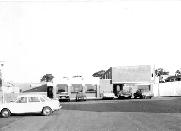 Black and white photograph of a flat-roofed 1960s brick pub with a row of arched windows and the words Border Reiver on the taller block, cars parked on the forecourt in front