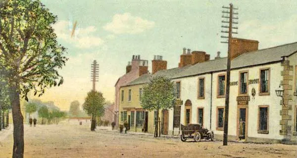 Tinted postcard of a long two-storey whitewashed hotel with stone quoins and a hanging lamp on a wide, empty street, with an early motor car outside, telegraph poles and young trees along the pavement